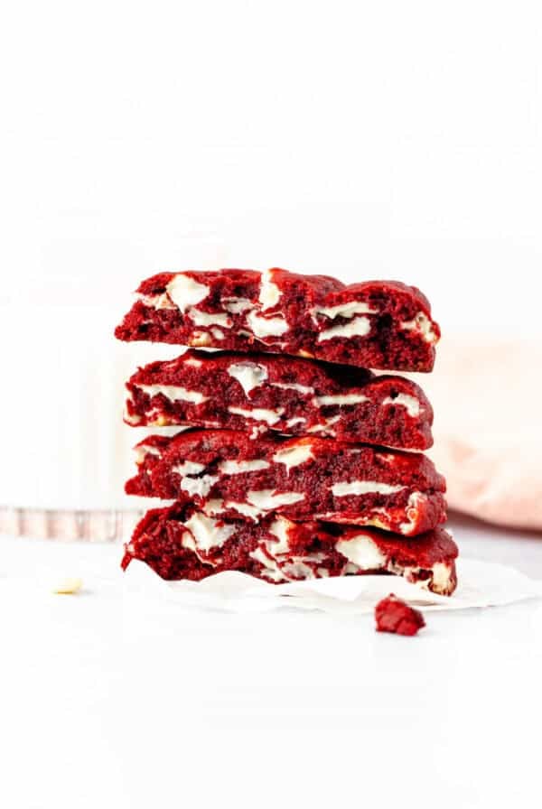 bakery style red velvet cookies, broken in half and stack on top of one another