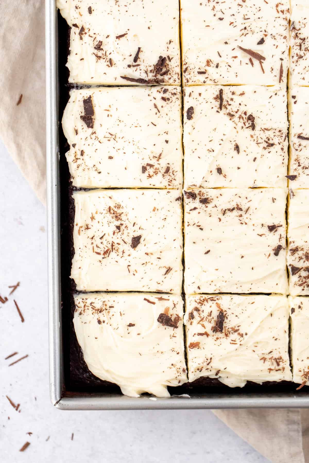 Sheet pan of chocolate cake with white chocolate frosting and chocolate shavings on top