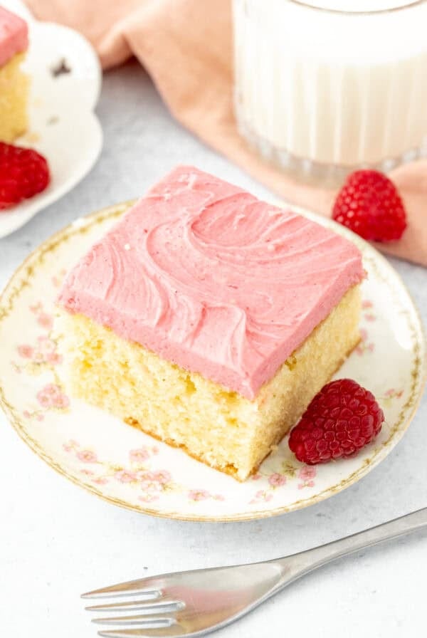 Slice of almond cake with raspberry frosting with a glass of milk