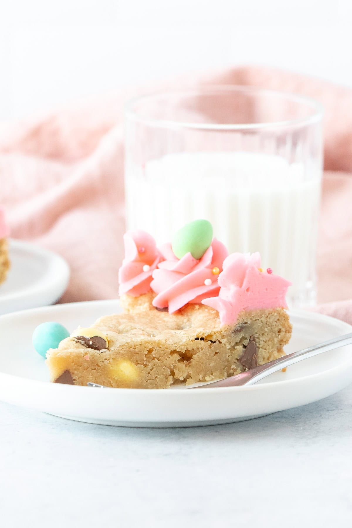 Slice of cookie cake made with Easter chocolate and decorated with pink frosting around the edges