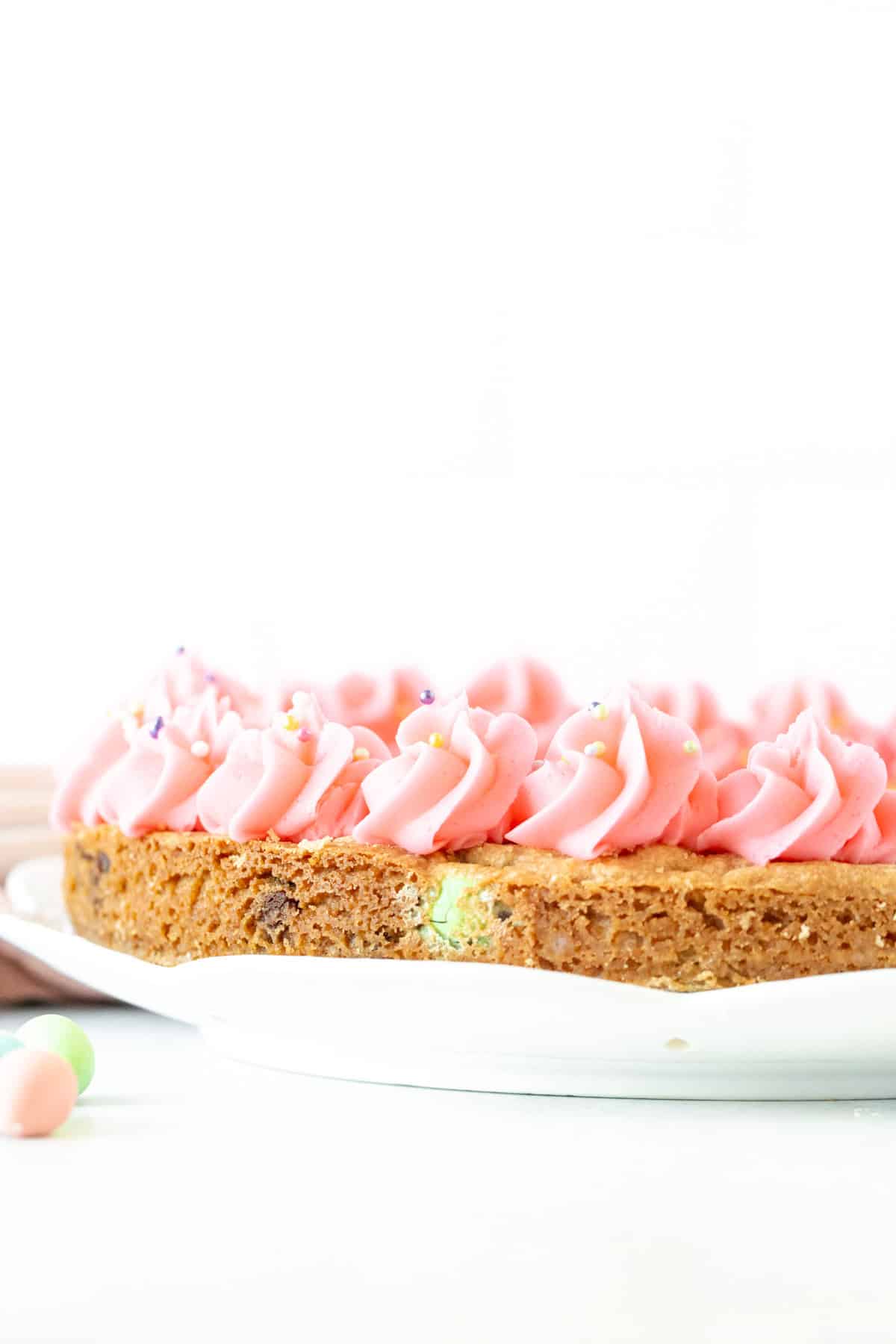 Cookie cake made with chocolate Easter eggs and decorated with vanilla frosting around the edges.
