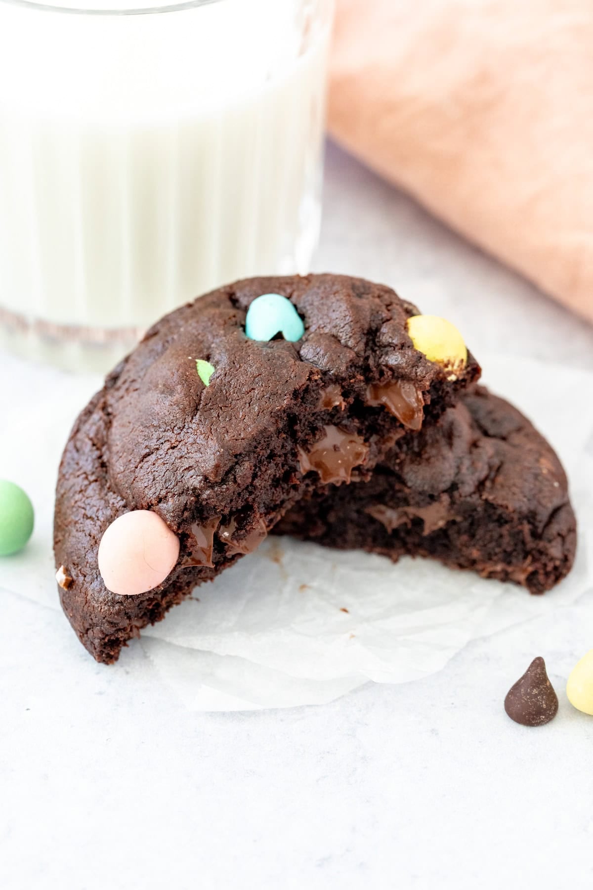 Chocolate mini egg cookie, broken in half with glass of milk