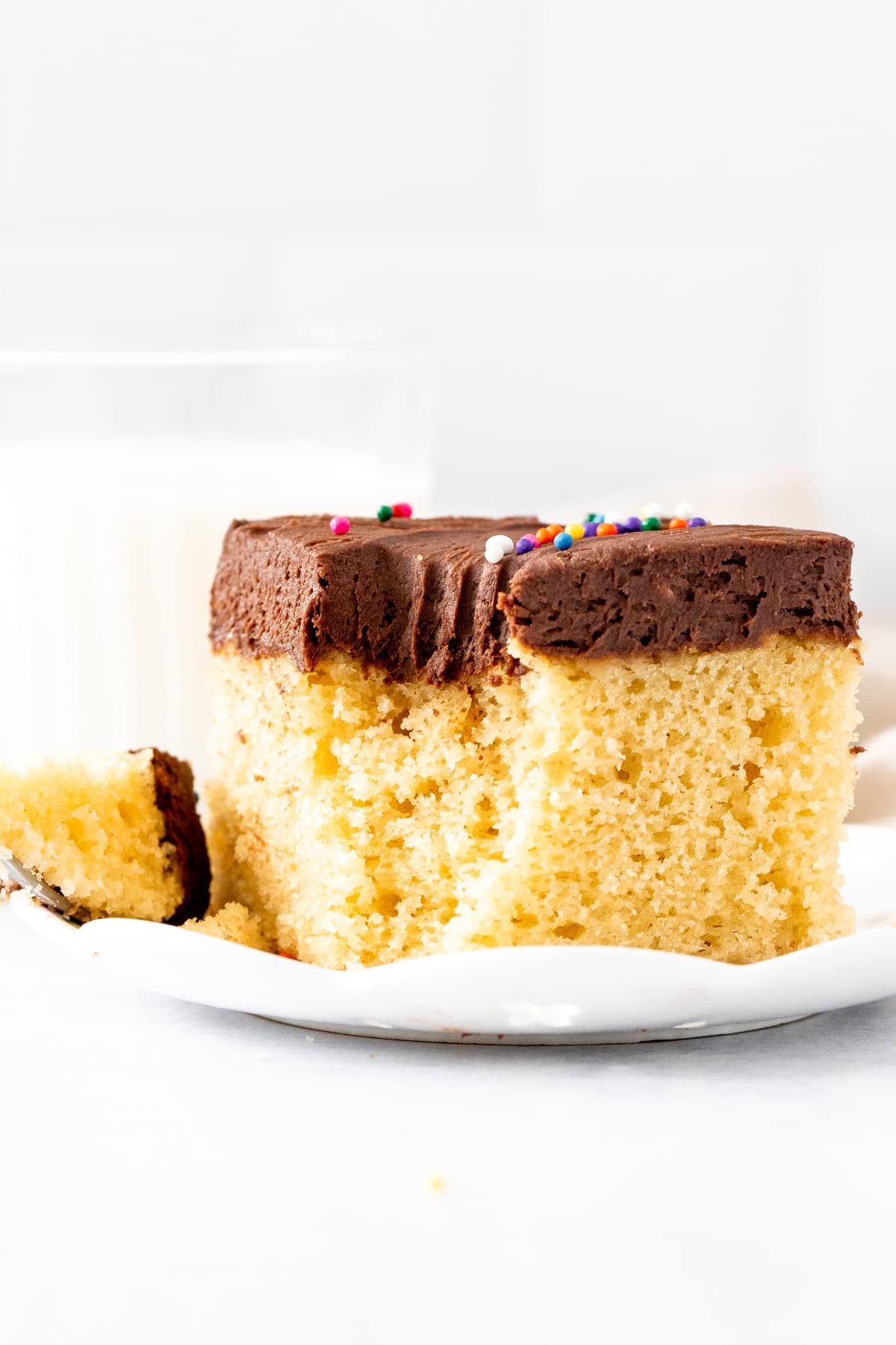 Slice of golden cake with chocolate frosting, with a bite taken out