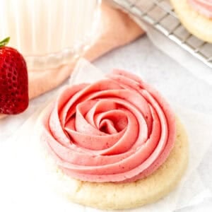 Sugar cookie topped with strawberry frosting piped into a rosette shape