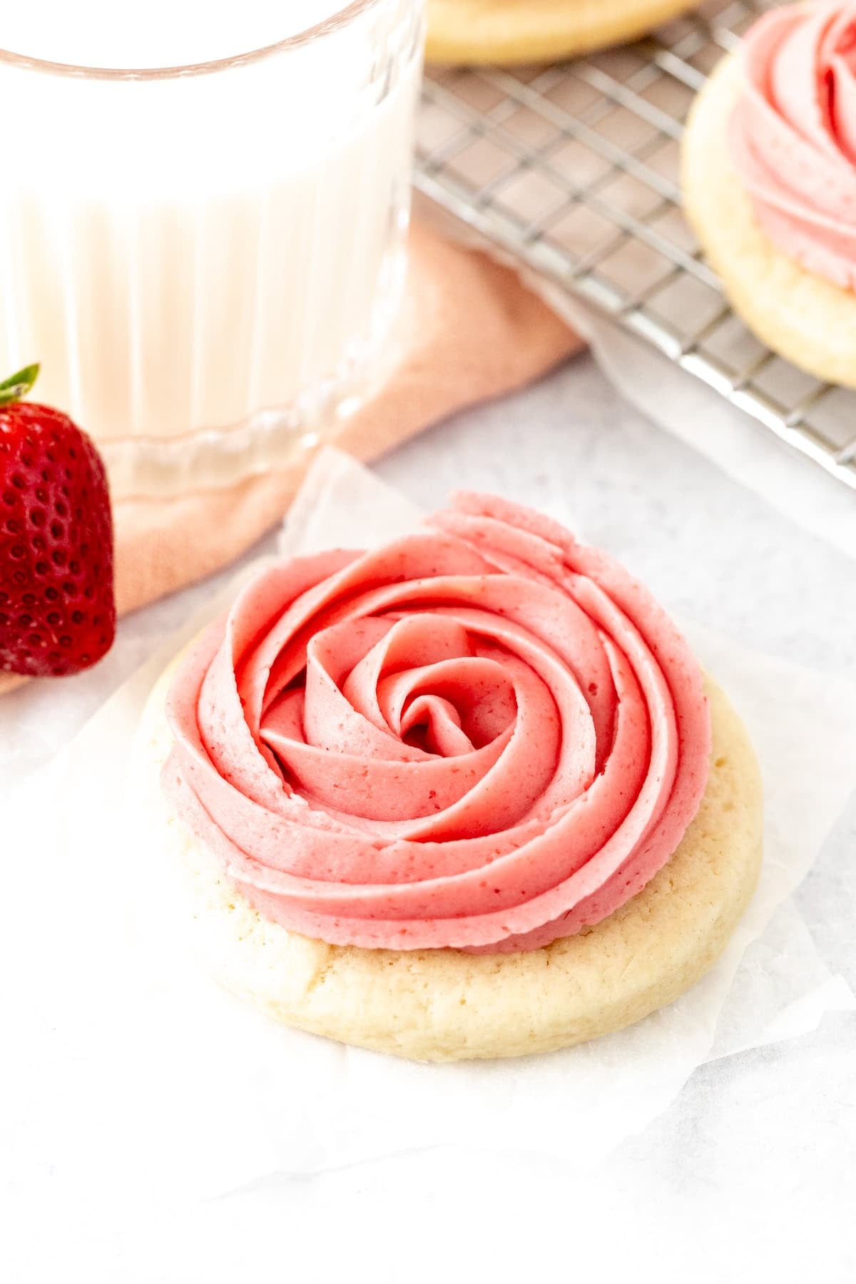 Strawberry frosted sugar cookie with a glass of milk