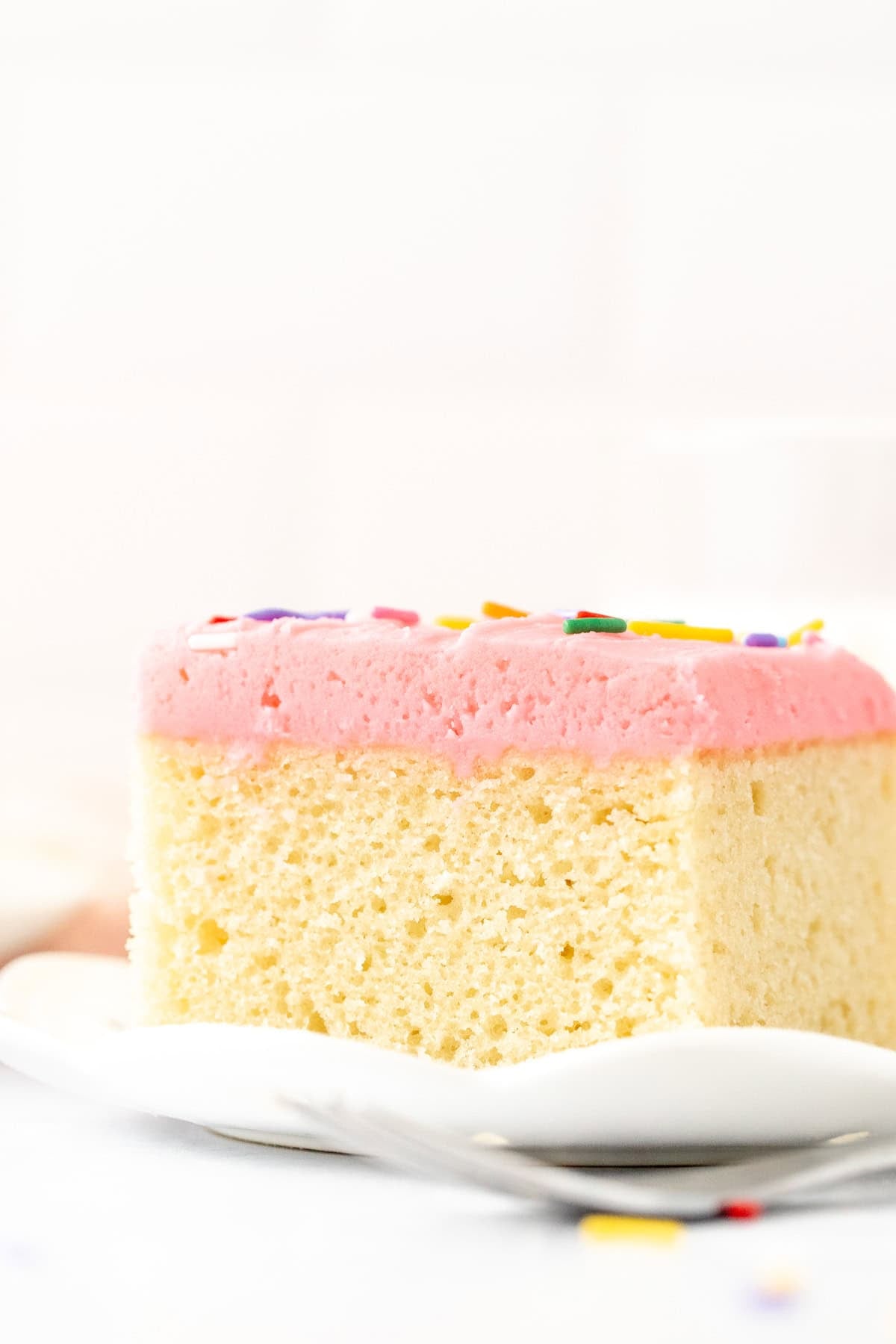 Slice of vanilla sheet cake with pink vanilla frosting