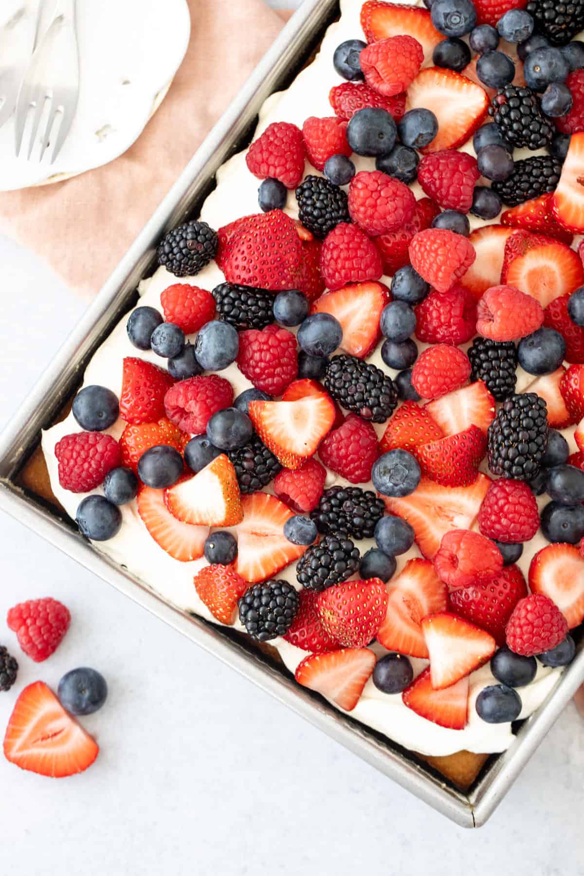 9x13 inch pan of sheet cake topped with whipped cream topping and berries