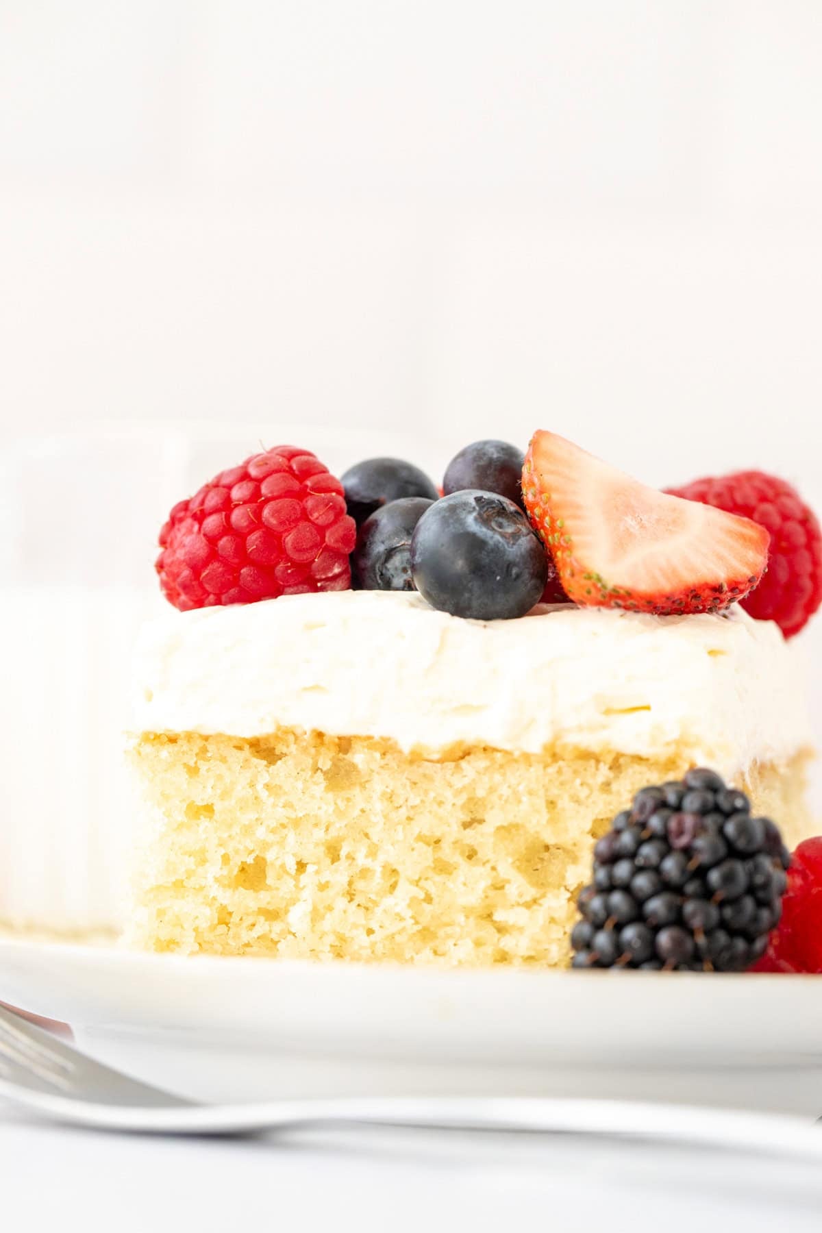 Slice of vanilla cake with whipped cream and fresh berries on top