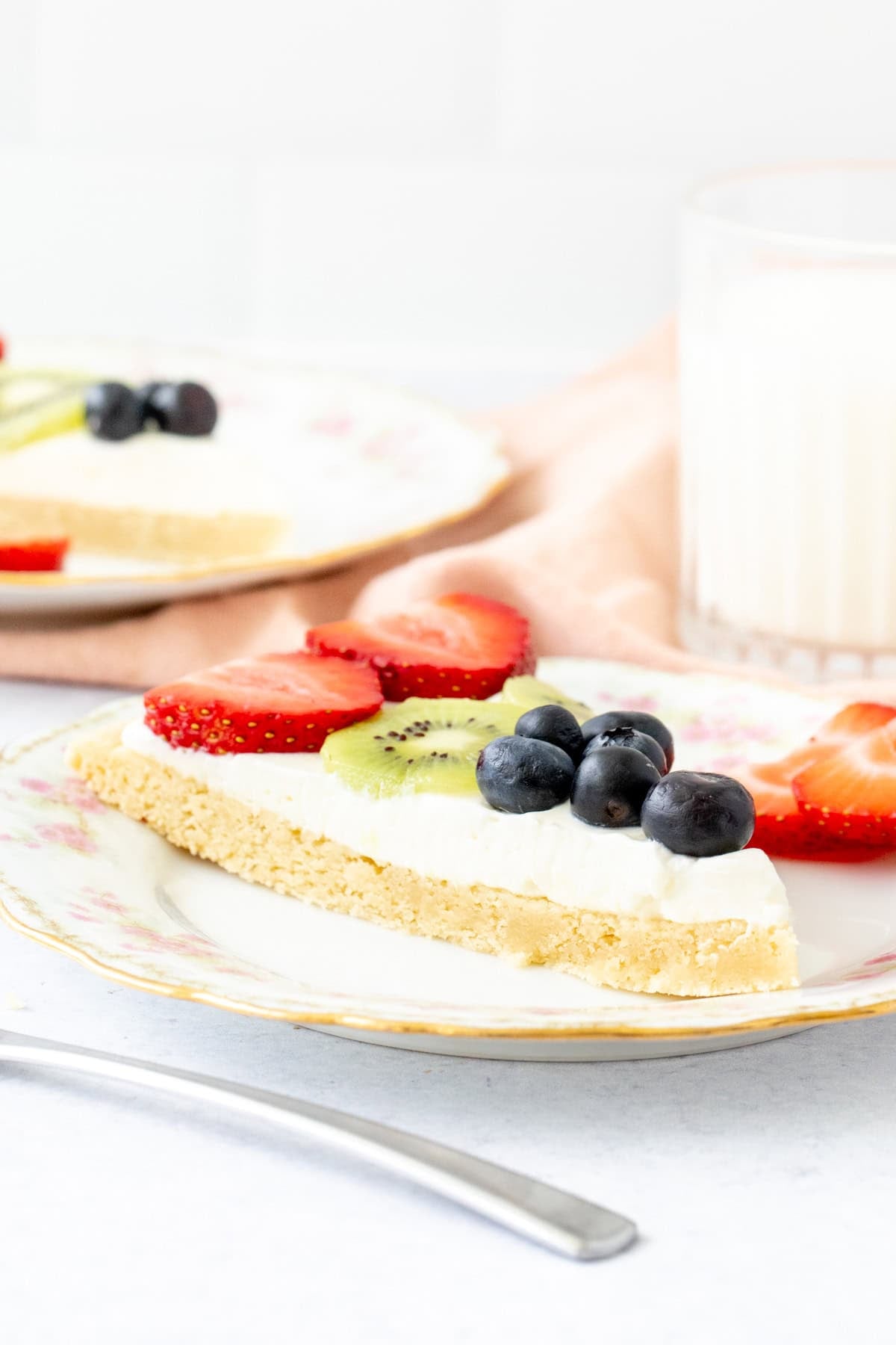 Slice of fruit pizza topped with whipped cream cheese frosting and fruit