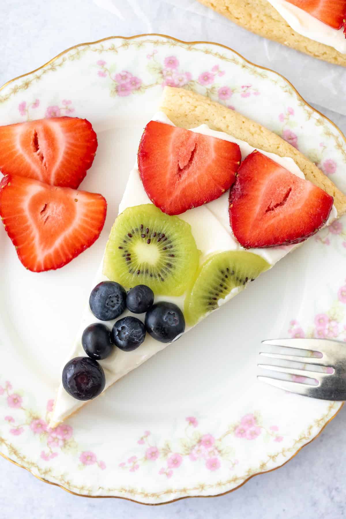 Slice of sugar cookie fruit pizza on a plate