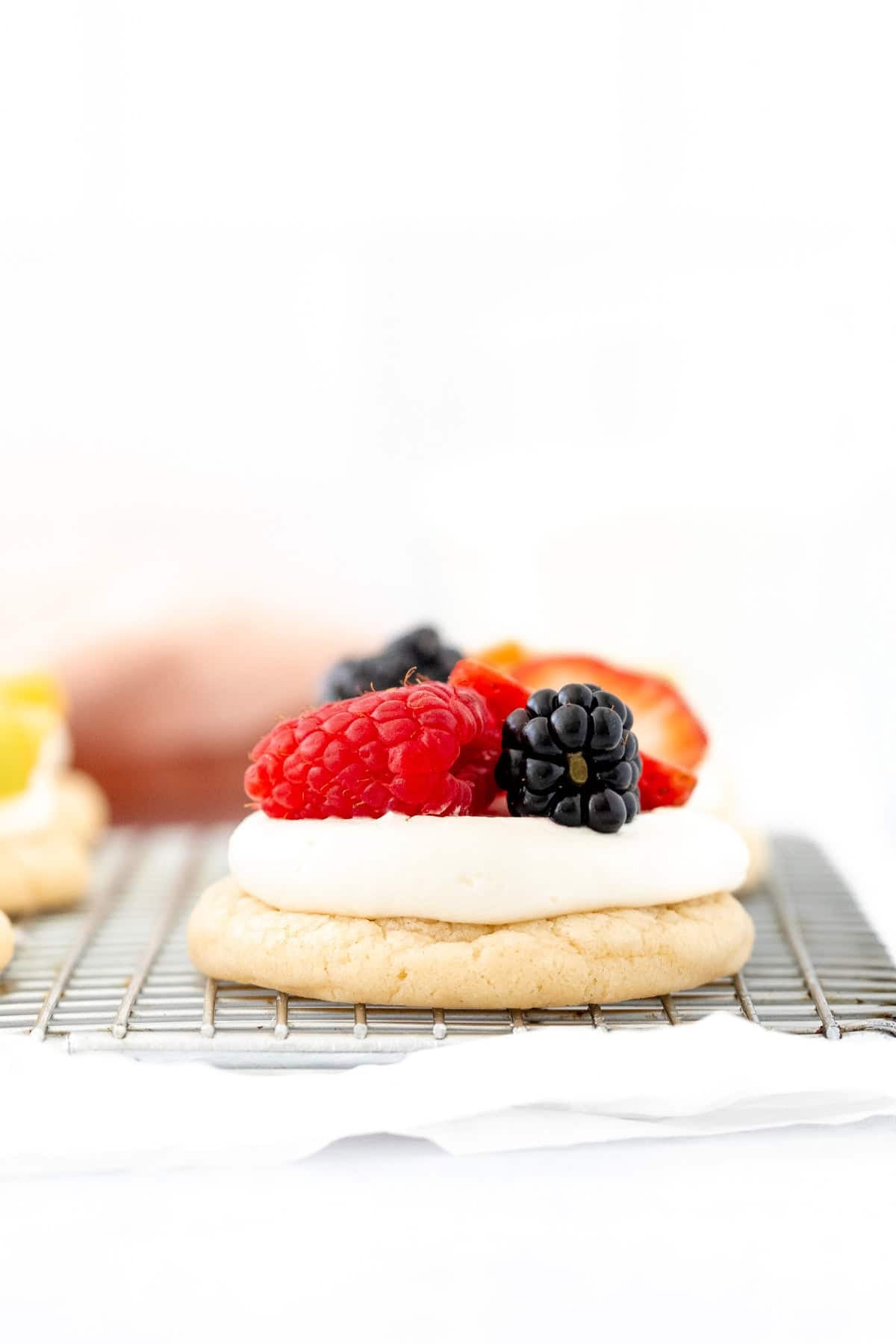 mini fruit pizza topped with berries on a cooling rack