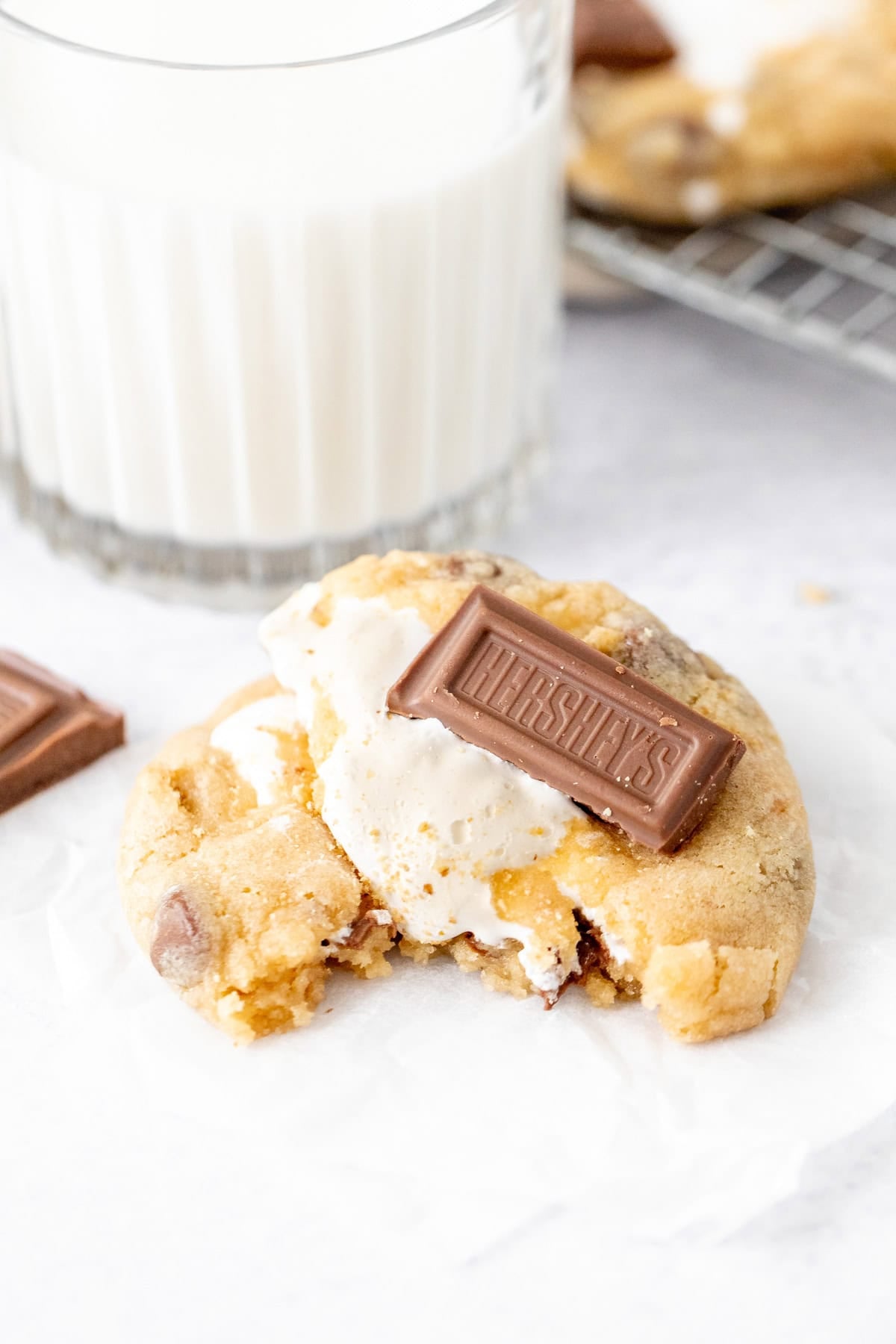S'mores stuffed cookie, broken in half with a glass of milk