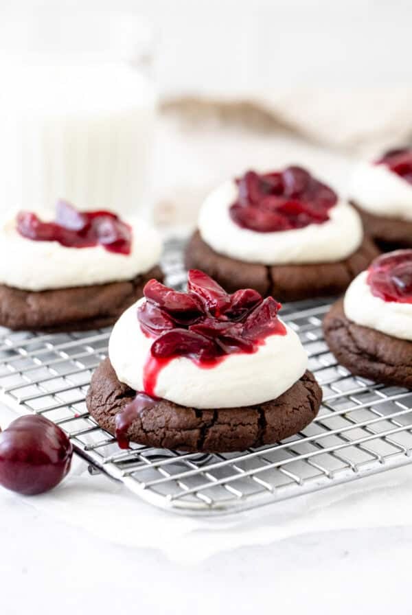 black forest cookies with whipped cream and cherry sauce on a cooling rack