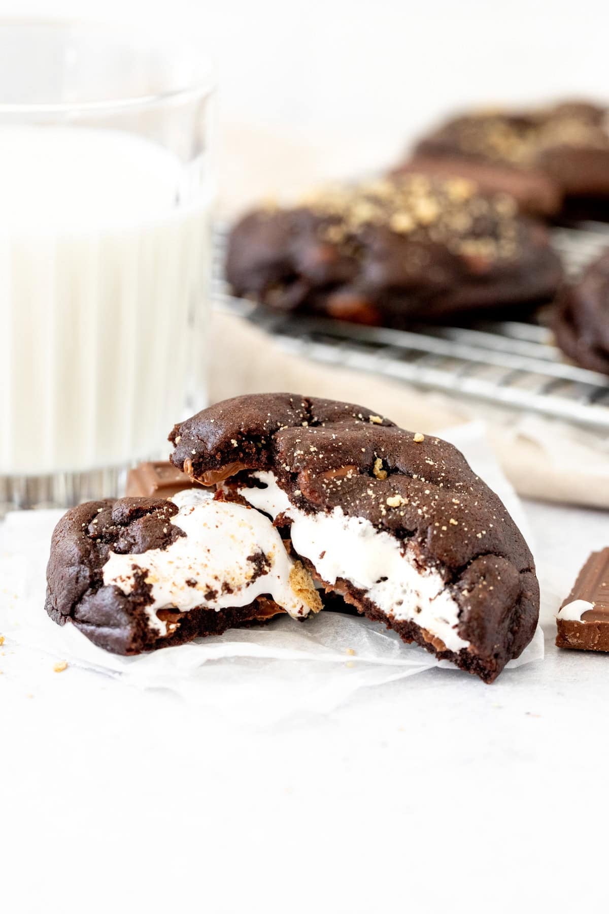 chocolate cookie stuffed with marshmallow, broken in half with a glass of milk