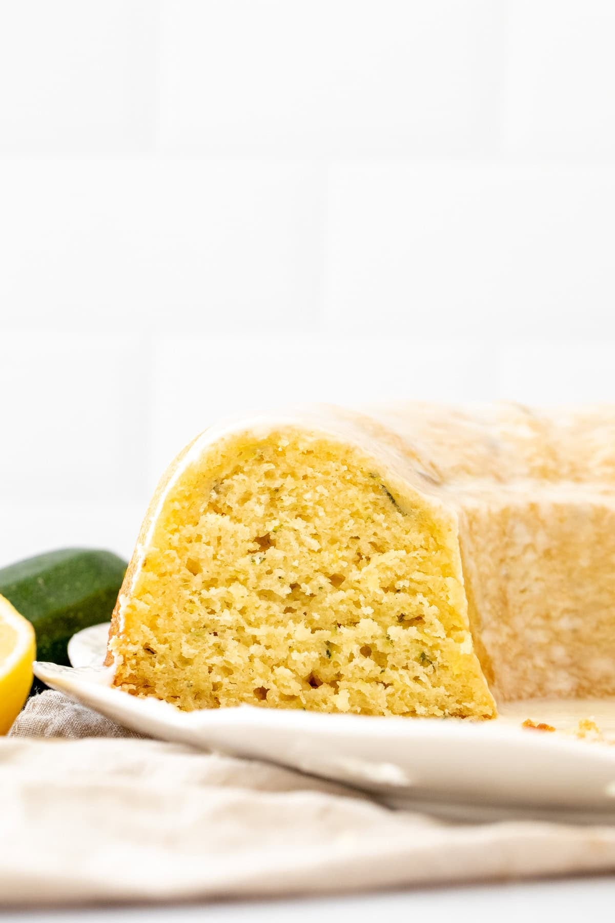 Lemon zucchini bundt cake on a white plate with slices cut out