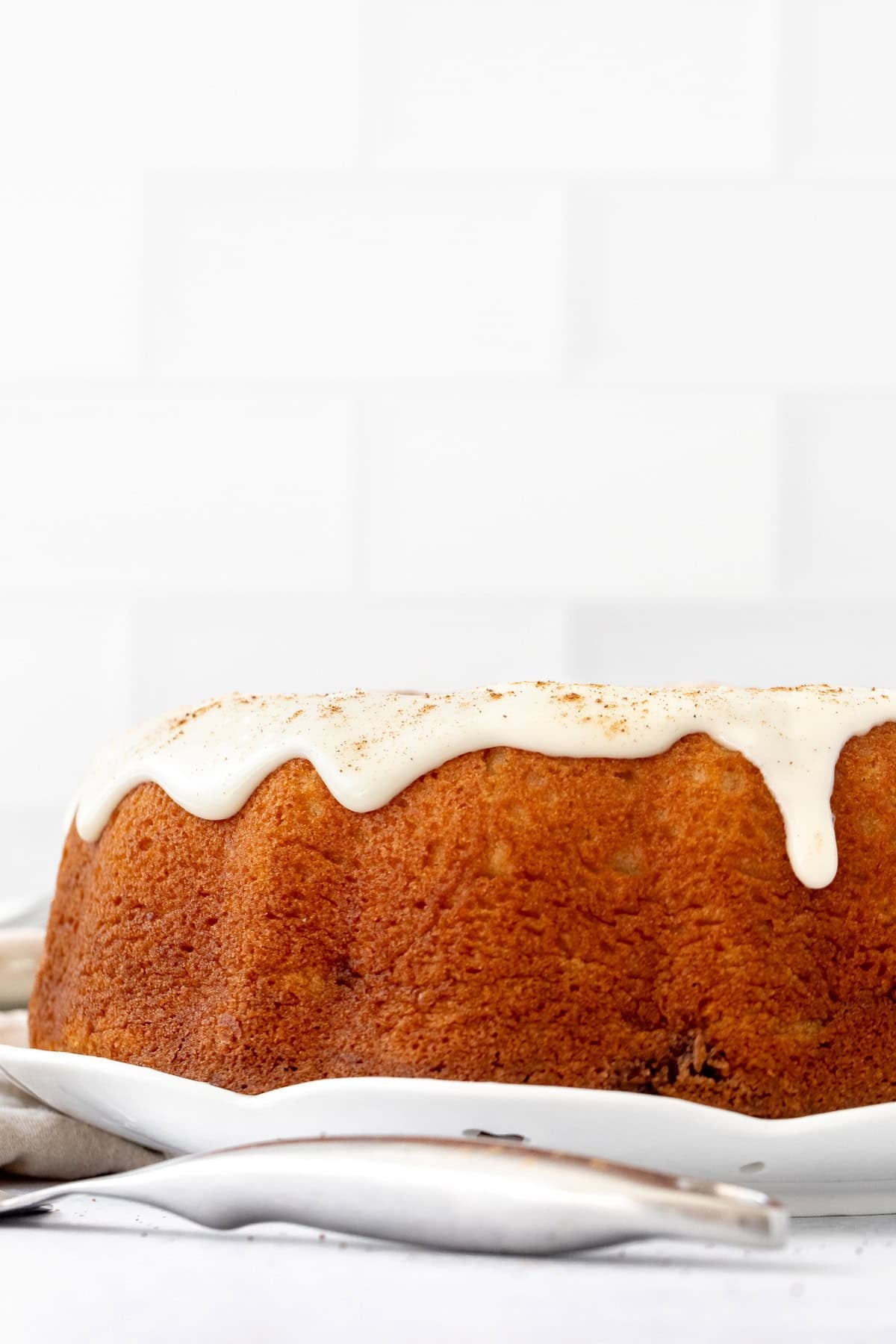 cinnamon roll bundt cake topped with cream cheese icing and a sprinkle of cinnamon