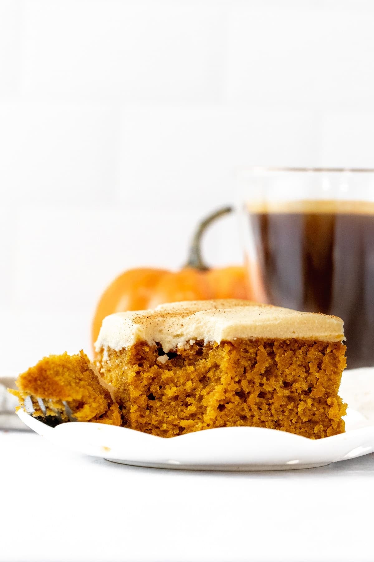 Slice of pumpkin cake with coffee frosting with a bite taken out.