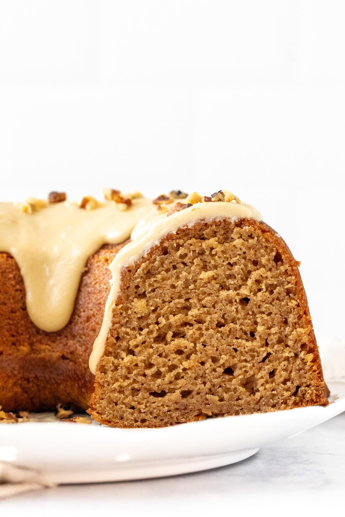 Spice bundt cake with maple icing, with slices cut out of the cake