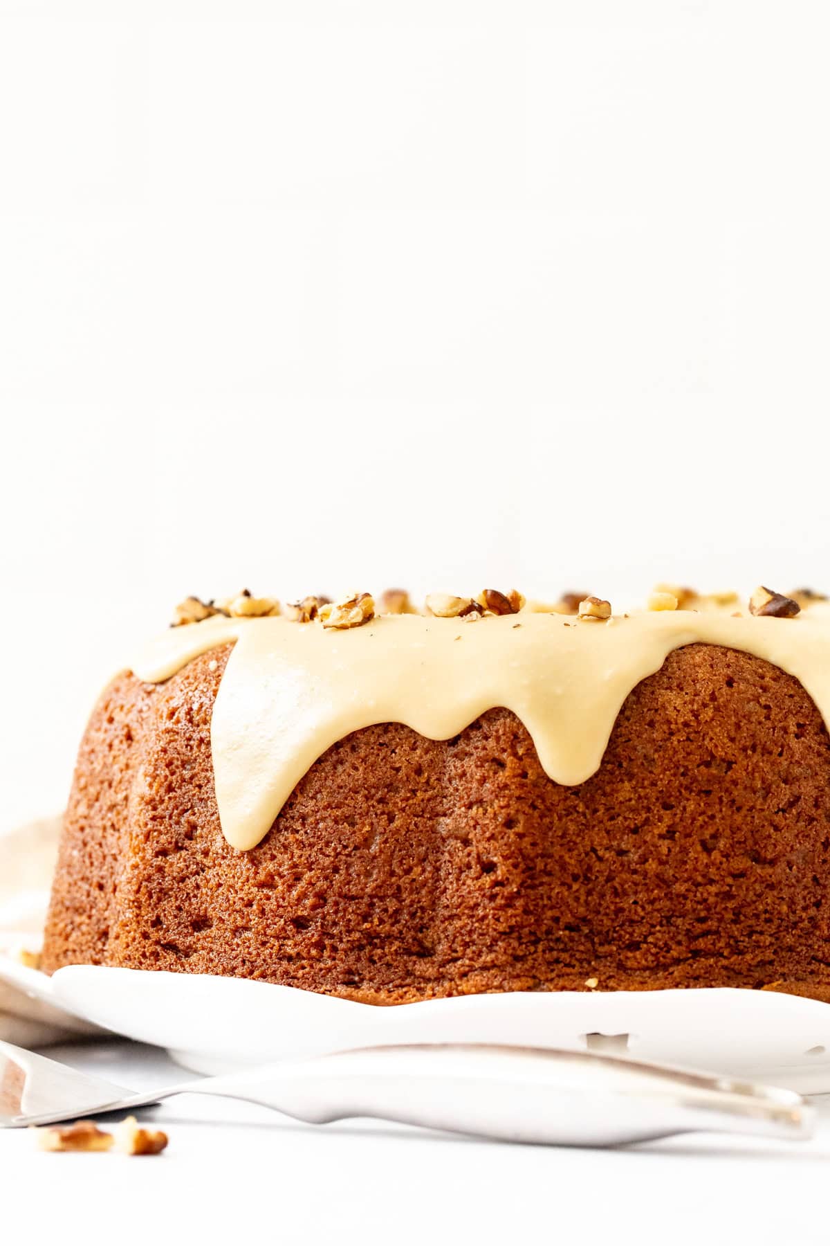 Spice bundt cake topped with maple icing and a sprinkled with chopped walnuts on top.