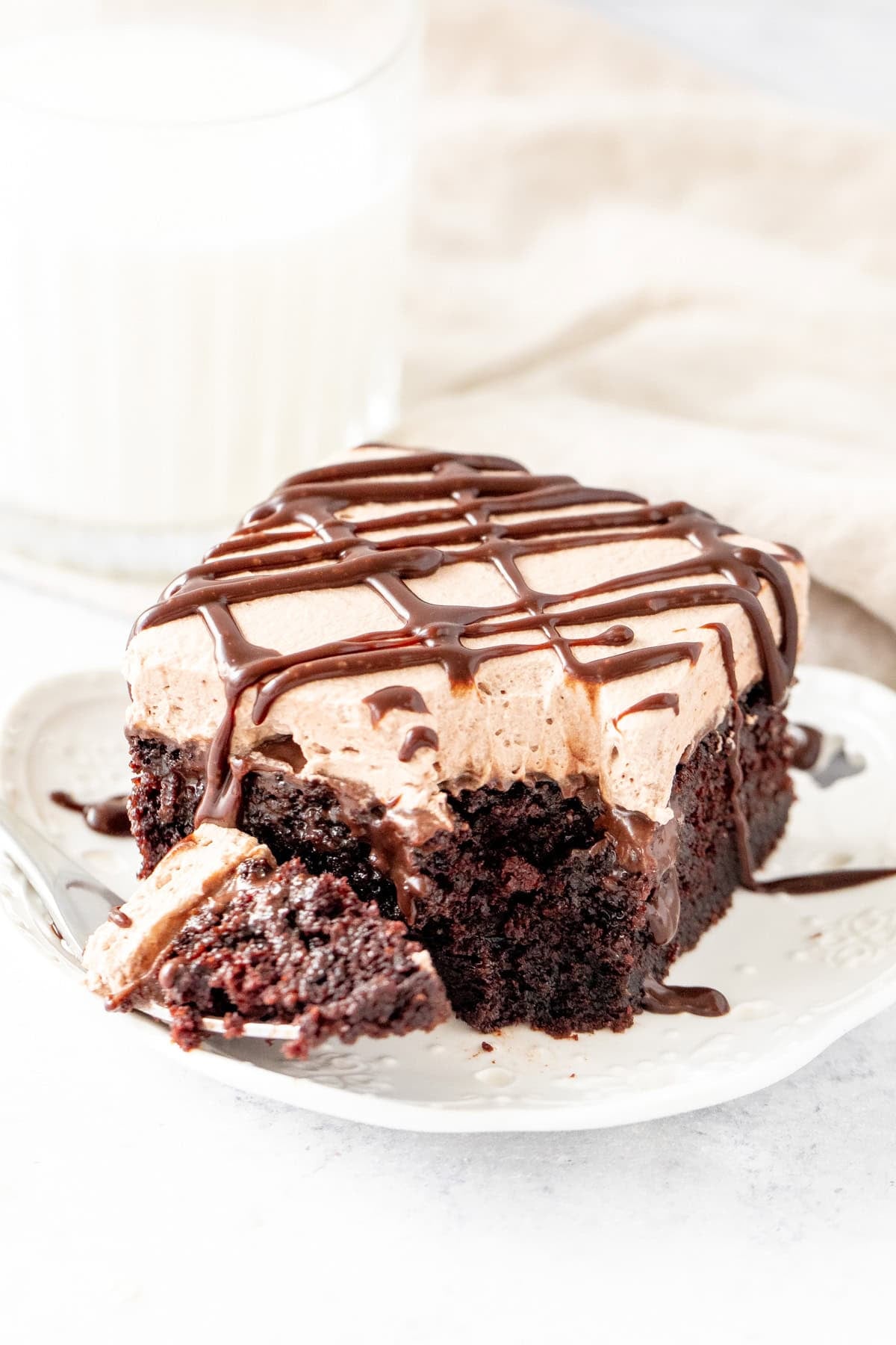 Slice of gooey chocolate poke cake with a bite taken out