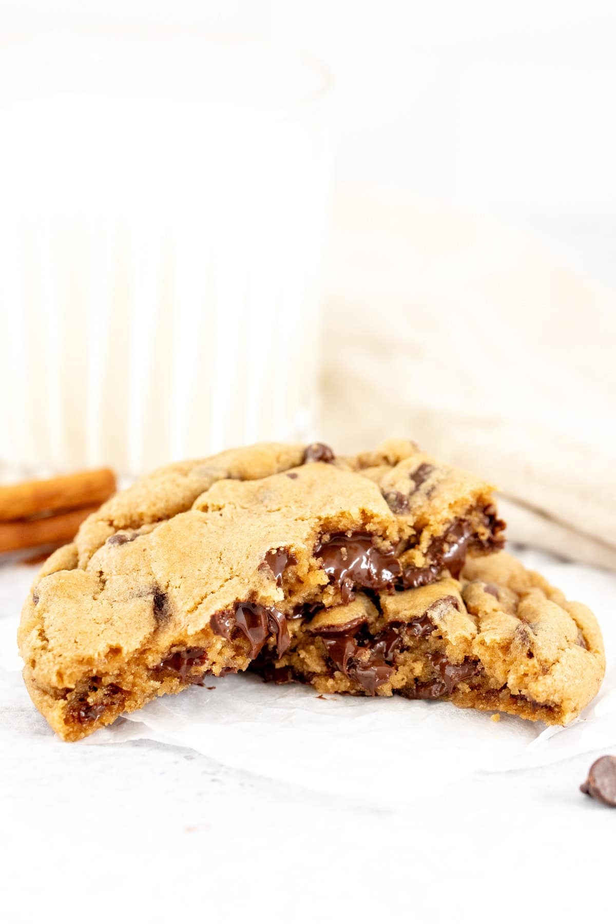 chocolate chip cookie, made with fall spices, broken in half with a glass of milk