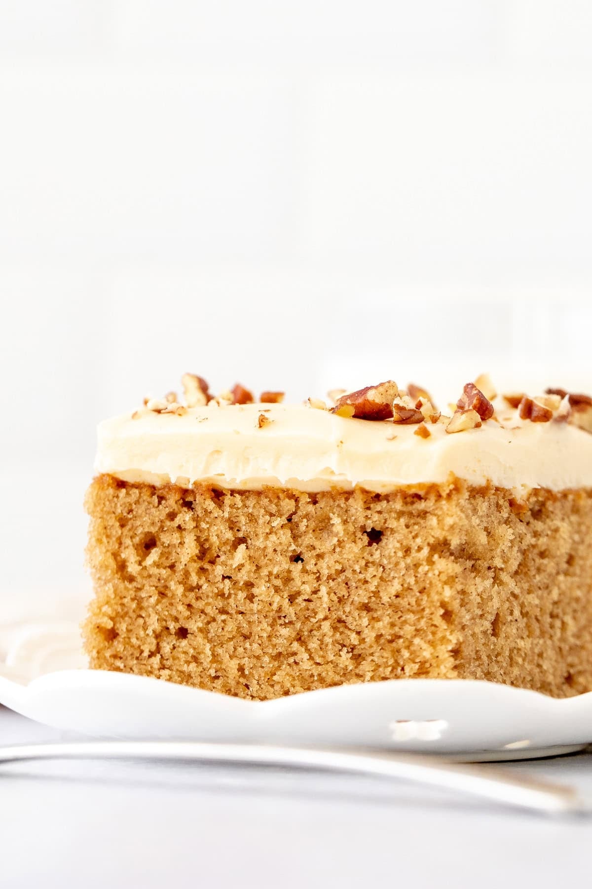Slice of moist maple cake topped with maple frosting and chopped nuts