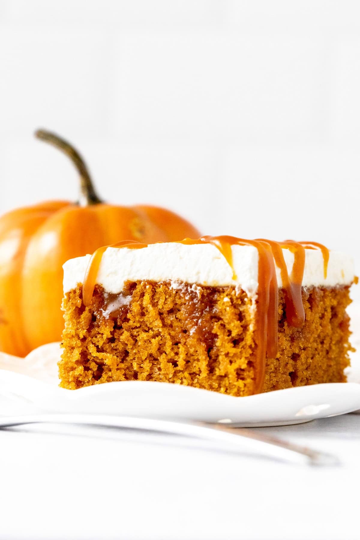 slice of pumpkin poke cake with caramel and whipped cream on top